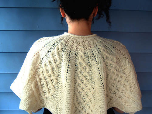 A fitted capelet with raised cable motifs