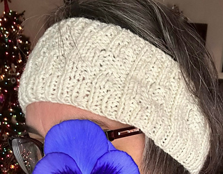 Cream headband with varied rows of ribbing shown worn over ears and forehead.