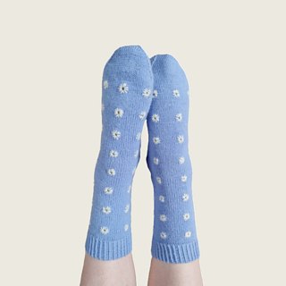 The same blue socks with white embroidery on feet in air.
