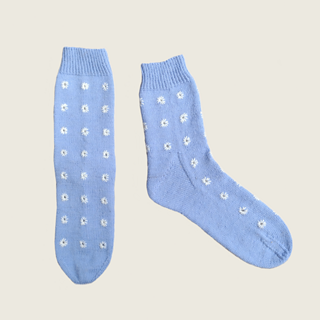 The same blue socks with white eyelet embroidery laid flat, one on it's side, on front on.