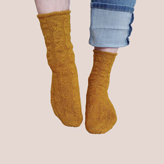 The same mustard-gold socks on standing feet, with one foot pointed.
