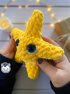 Crochet amigurumi pattern of a yellow Christmas star made with velvet yarn and big glittery eyes.