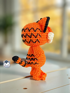Crochet orange cat amigurumi inspired by Garfield, featuring rounded cheeks, embroidered details and black stripes on the back.