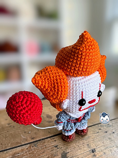 Handmade Pennywise amigurumi inspired by IT featuring a red balloon, a geek crochet pattern PDF perfect for Halloween and horror fans.
