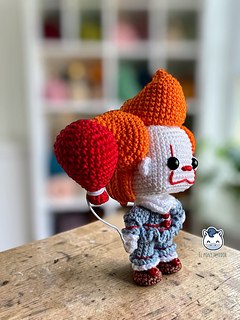 Handmade Pennywise amigurumi inspired by IT featuring a red balloon, a geek crochet pattern PDF perfect for Halloween and horror fans.