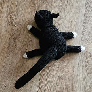 Black and white knitted cat splat on the floor