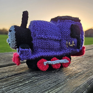 Charlie knitted toy train on an outdoor bench in sunset