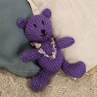 Knitted teddy bear with amethyst necklace for February birthstone bear