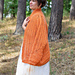 Woman draped in a warm, pumpkin-colored crochet cardigan, highlighting its cozy texture and stylish design.
