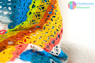 Macro view of lightweight crochet fabric in modular shawl pattern, showing drape and structure