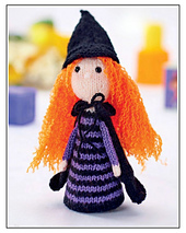 Monica the Witch knitted toy in black and purple DK yarn with orange hair, standing approximately 23cm tall