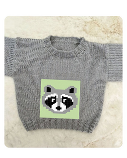 Grey baby jumper knitted with the Bandit raccoon knitting chart on a green panel, Blank Canvas Baby Sweater flat lay