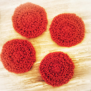 Four red knit coasters, spread out.