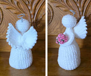 A handmade crochet angel figure with detailed wings, a round head, and flowing gown, displayed standing upright.