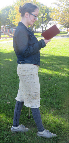 Image Description: A woman wearing a cream pencil skirt knit in stocking stitch.  The skirt comes to just below her knees and is edged with eyelets.