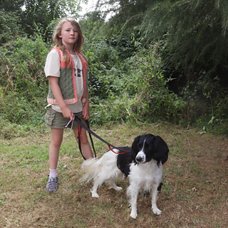 8 year old wearing 'age 10' size, in shades of peach and green, in an outdoor countryside setting. Child is holding a dog on a lead in tge photo.