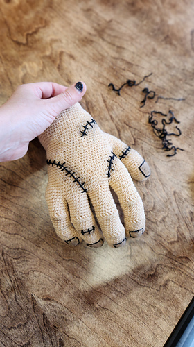 Crocheted poseable Thing hand from Wednesday series, a life-sized amigurumi perfect for Halloween decor.