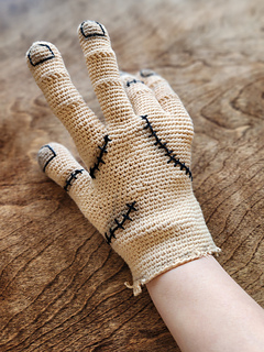 A person wearing the finished crochet Thing glove, a realistic DIY cosplay accessory.