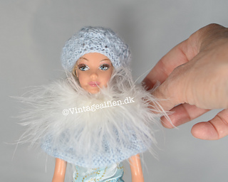 A Barbie doll with a knitted beret with mock cables.
Please note the pattern for the cape is not included.