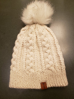 white cable knit hat lying flat on a table