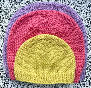 newborn yellow hat on top of red child hat on top of lilac adult hat