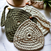 Neutral farmhouse-style crochet trivet in cotton yarn, styled on a wood cutting board beside a mug and utensils.