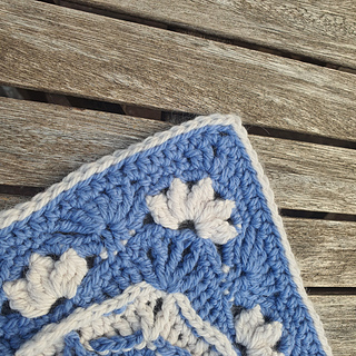 close-up view of corner with edging of blue and grey crocheted fancy granny square