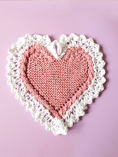 Heart-shaped knitted cloth with white lace edges on a pink background