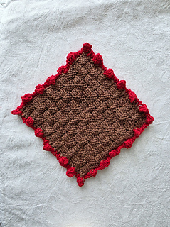 Brown basketweave knitted square with red bobble border.