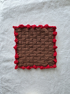 Brown basketweave knitted square with red bobble border.