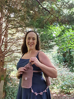 Woman in forest holding brown and pink crocheted bag with flowers
