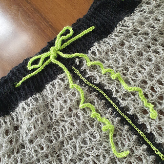 Black and grey crocheted fabric with a bright green bow and cord detail on a wooden surface