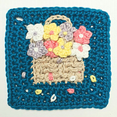Crocheted square with a beige basket full of colourful flowers on a teal background. Petals scattered around