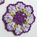 crocheted dark and light purple flower coaster with green detail
