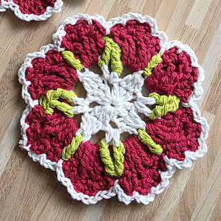 crocheted red and white flower coasters with green detail