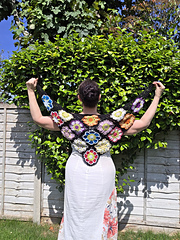 Black lace triangular shawl with bright floral granny squares held behind wearer