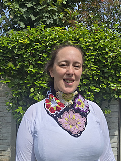 Black lace neckerchief with bright floral granny squares worn with point at front, tied at back