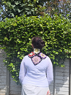 Black lace neckerchief with bright floral granny squares worn with point at back, tied at front (from rear)