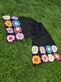 Black lace rectangular shawl with bright floral granny square border at short ends laid flat