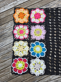 Black lace rectangular shawl with bright floral granny square border at short ends draped over table