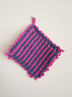 Pink and navy crocheted cloth hanging on a light coloured wall