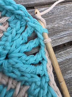 Turquoise and beige lace edging crochet in progress on a wooden hook