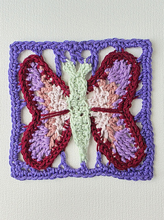 crochet lace square with colourful butterfly design  in blues purples, pinks and green 