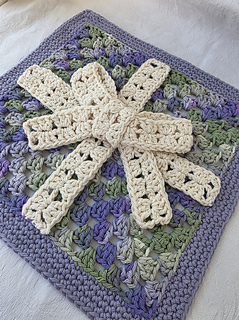 Crocheted lavender, green, and cream granny square decorated with cream crocheted ribbon