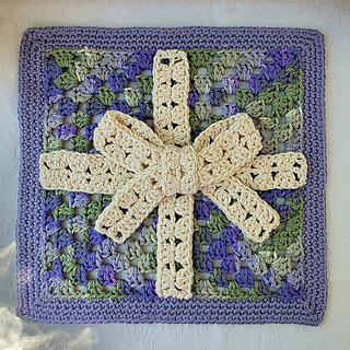 Crocheted lavender, green, and cream granny square decorated with cream crocheted ribbon