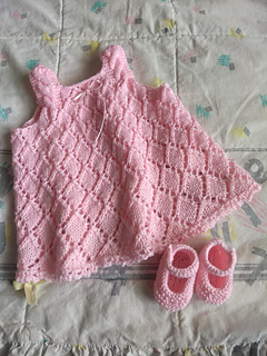 pink knit dress and baby booties lying flat