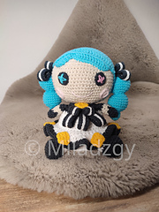 Gwen from League of Legends, crochet toy made by amigurumi technique. Used turqoise blue, dark gray, white, yellow, beige, pink and light pink yarn. Front view. Smiley face, white dress with dark gray outbound, blue and pink pupil in button eyes, blue hair in two blue curled up braids.