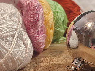 White, pink, yellow, green, brown yarn skeins, plain Christmas bauble.