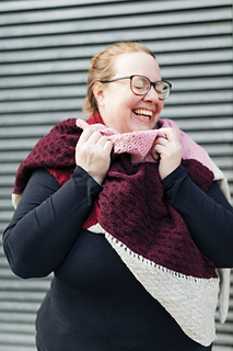 Lena snuggles up in Wayfarer, laughing at something our photographer said off camera. The texture of the stitch patterns plays beautifully with the different yarn colors.
