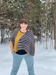Model is 5'-7" with 46" bust wearing Size 1, which creates a more cropped fit. This styling shows the piece squarely on the shoulders with the stripes in the horizontal direction. This styling creates a boxier fit and shorter "sleeves".